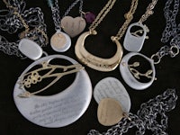 a group of silver and gold necklaces with words on them