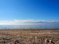 a beach with a lake and mountains in the background