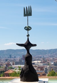 a black sculpture in front of a city